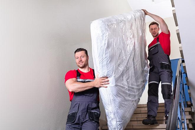 team of workers maneuvering a box spring through a doorway in Angelus Oaks